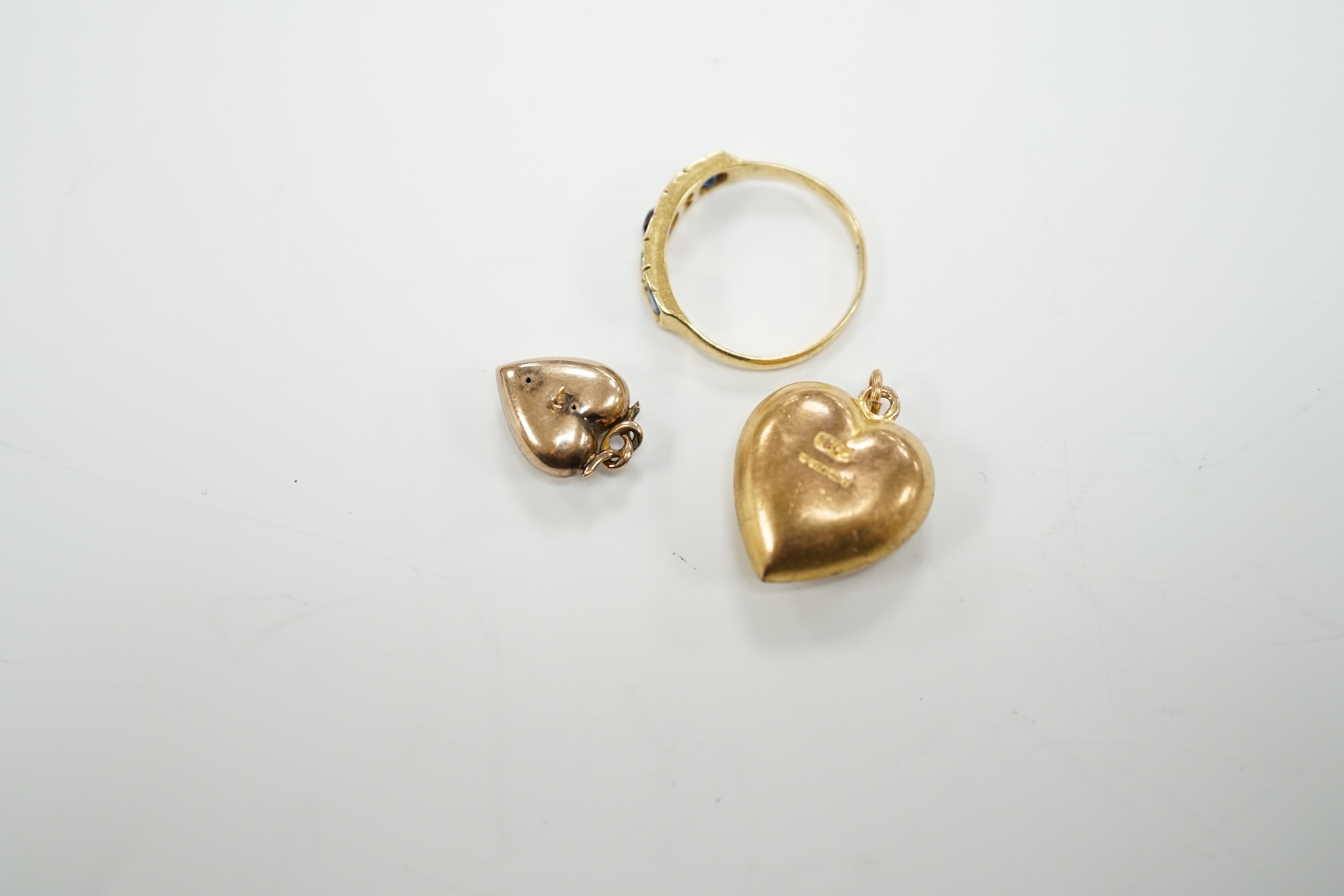 Two late Victorian 9ct and gem set heart pendants and an 18ct and gem set ring.